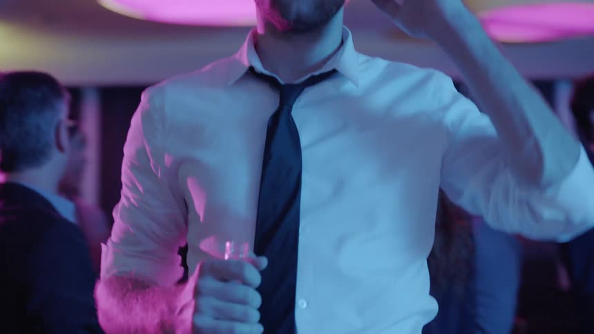 A man is holding a bottle of alcohol at a party