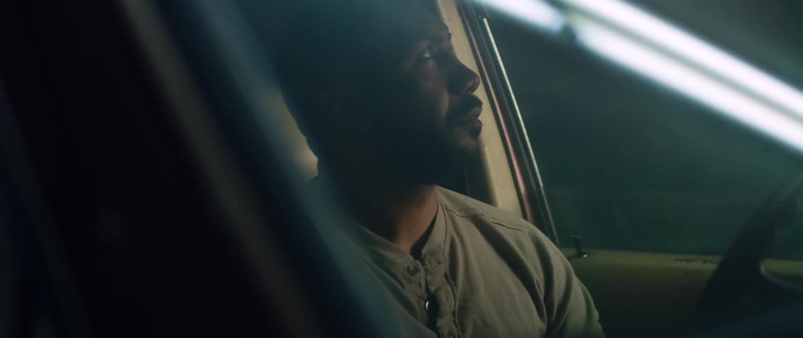 A man sits in his car at night and nervously looks outside