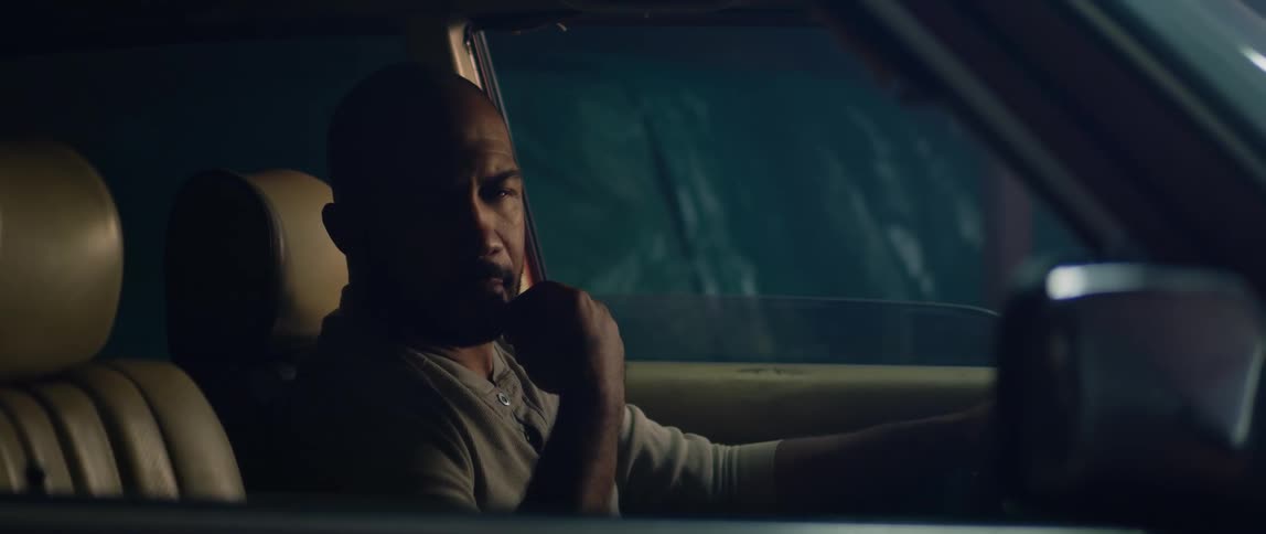 Man sits thinking in drivers seat of car parked near the woods