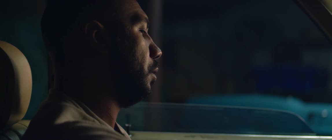 A man waits inside his car in a parking lot