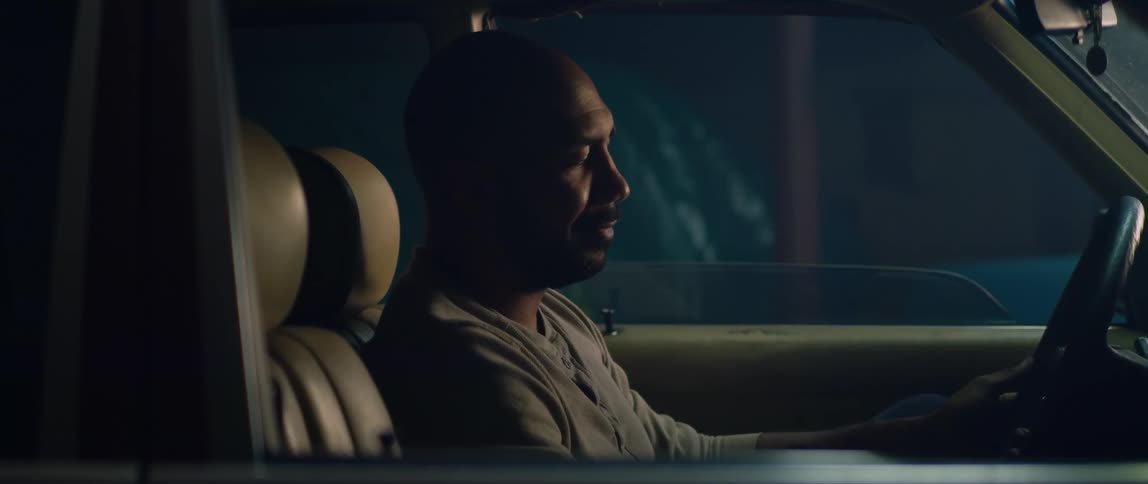 A man smiles to himself while sitting in his parked car