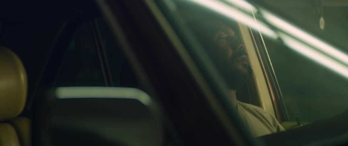 A man sits in his car with his head against the headrest and he closes his eyes