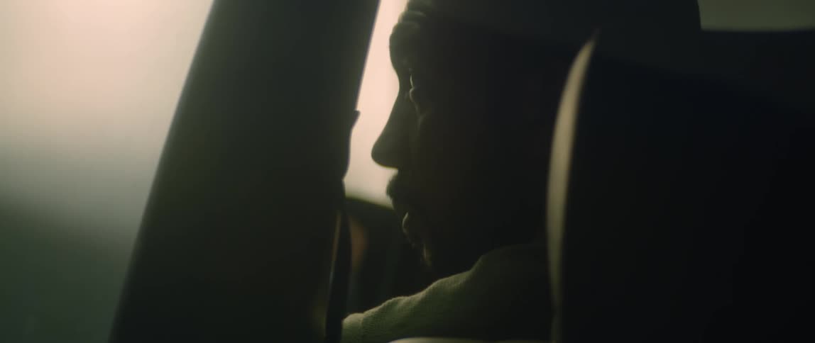A man turns his head to look out the window of a car