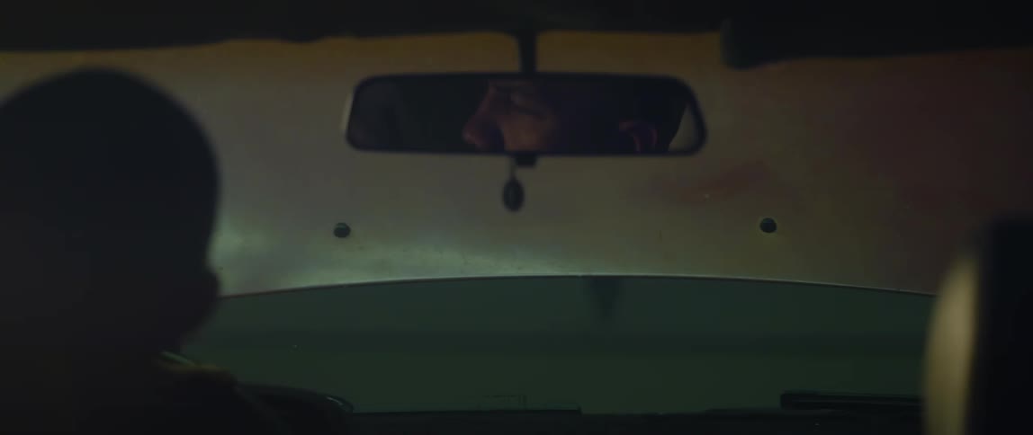 A man sits in his car with the hood up at night