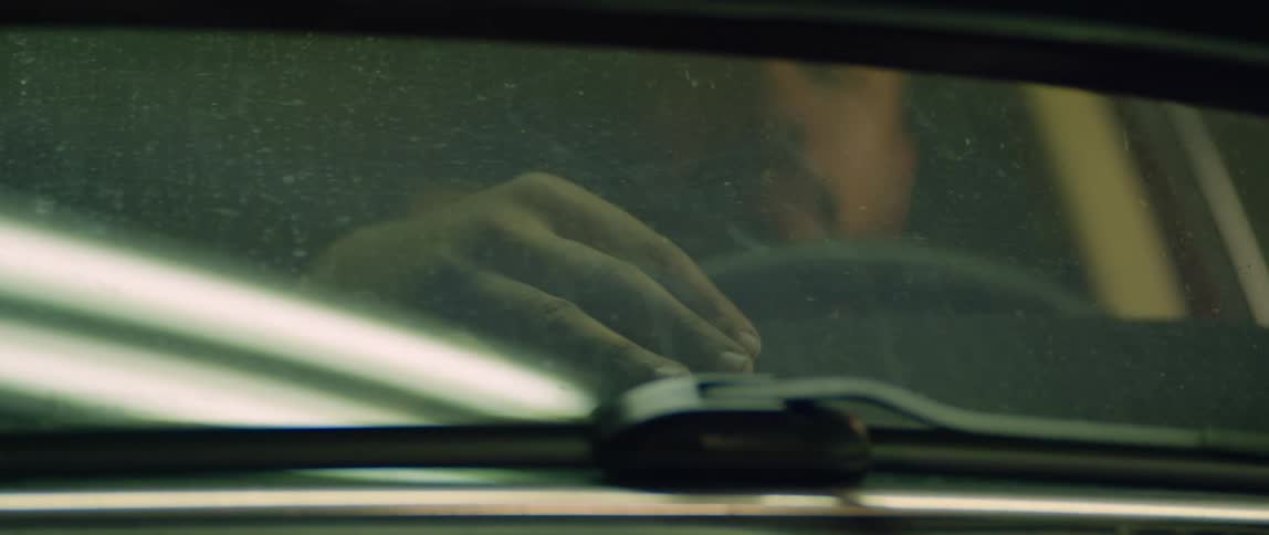 Man strokes hand over car interior while sitting in drivers seat