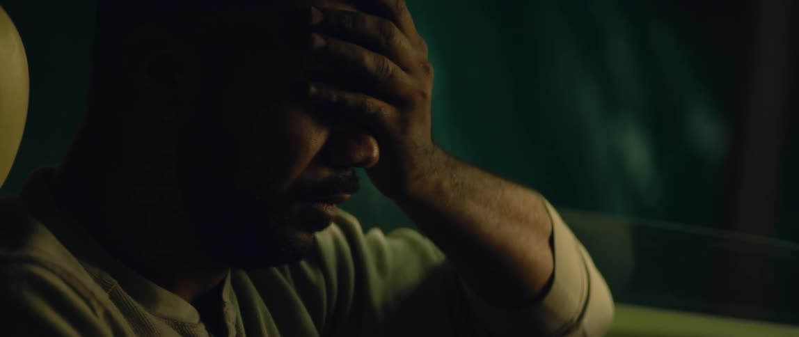 A man sits in his car at night and rubs his foreheads and runs his hand over his face