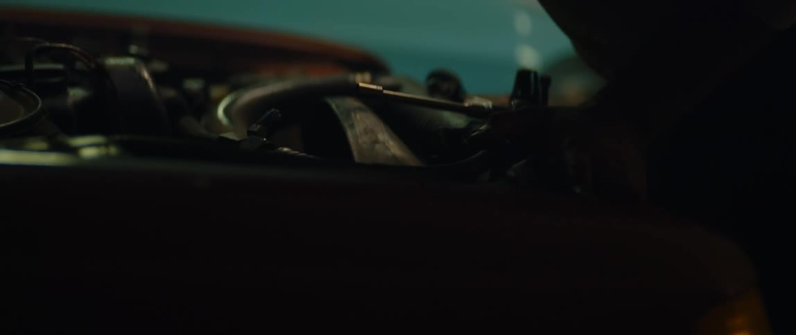 A man is outside looking under the hood of his automobile