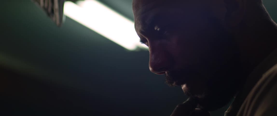 A man is thinking as he stands in a room with an overhead light