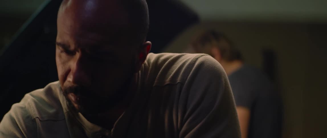 Two men are in a room with one looking at the other one