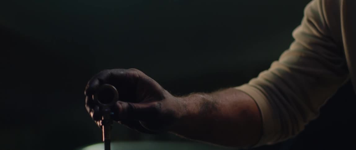 A man is replacing the dipstick into an engine of a car