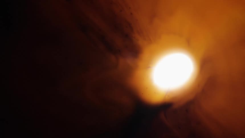 A light flashes in a hole surrounded by an orange fluid