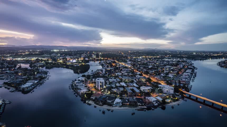 Boats travel around an island and cars travel across the bridges as dawn turns to night