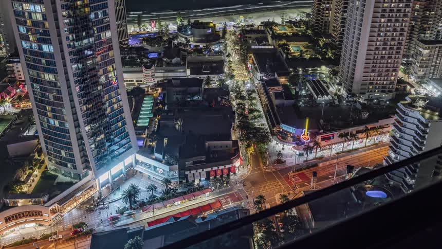 A balcony overlooking a busy waterfront tourist attraction with colorful lights and signs flashing