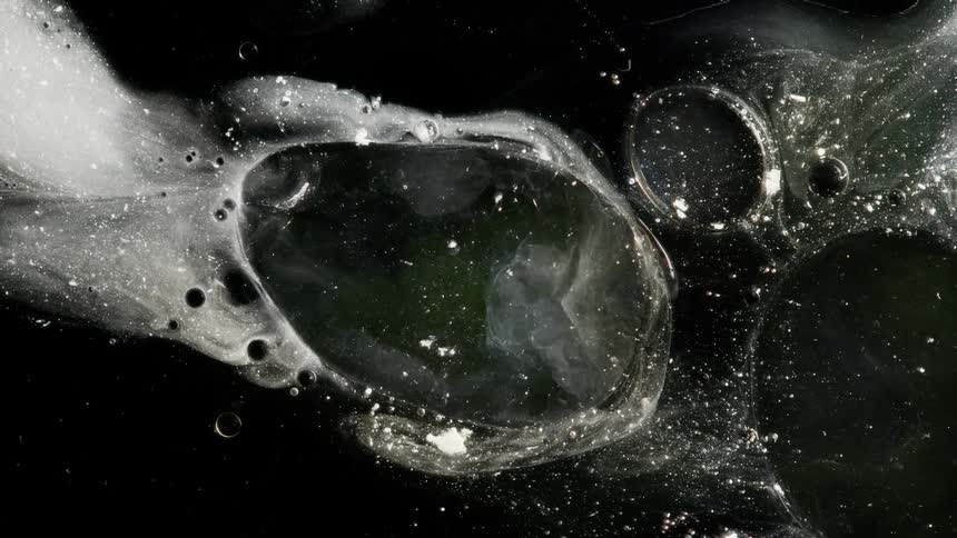 A cloudy cell of liquid moves and flows across black