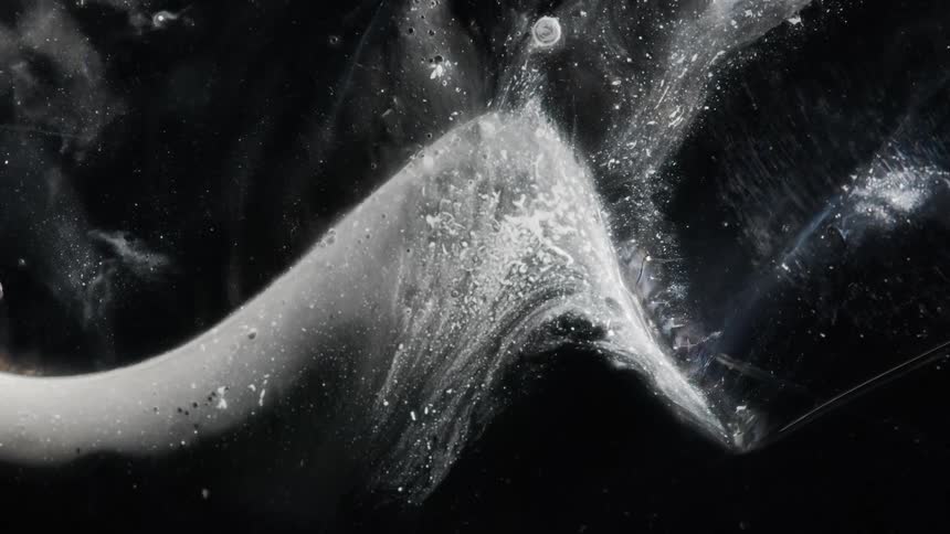 A smoky wave flows and shifts against a black background
