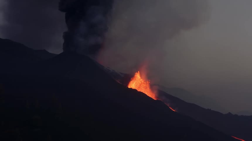 Dark smoke billows up in to the sky as lava spews in to the air