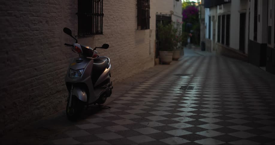 A moped is parked in an alley of an old town
