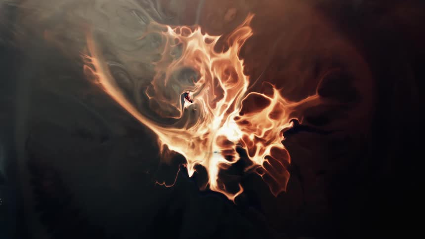 A flame like liquid emits smoke as it spreads out in the darkness