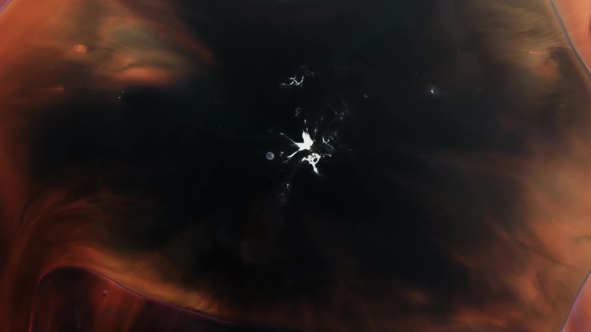Small white objects move inside a bubble as it grows across an orange and black organic environment