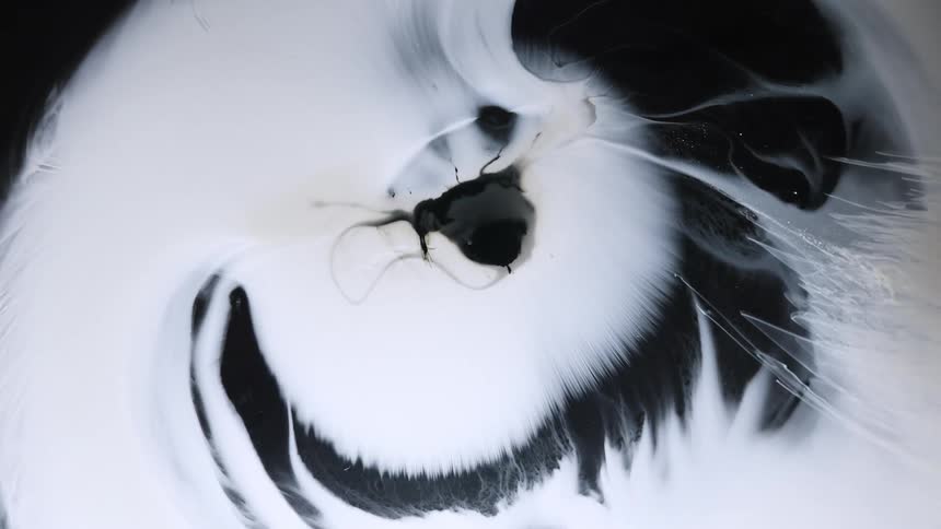 Smokey lines are emerging from the edges of a white cloudlike object in the darkness and the eye in the middle is changing shape as the white fades to black