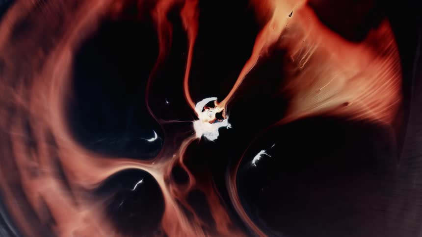 Small orbs leave a white center substance as a flame like liquid spreads out in the darkness