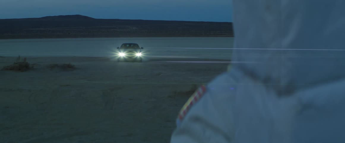 A vehicle drives along the beach at night