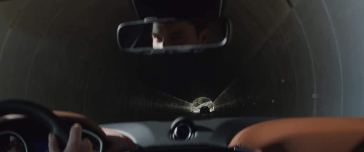 A man drives from one tunnel into the sunlight and enters another mountain tunnel