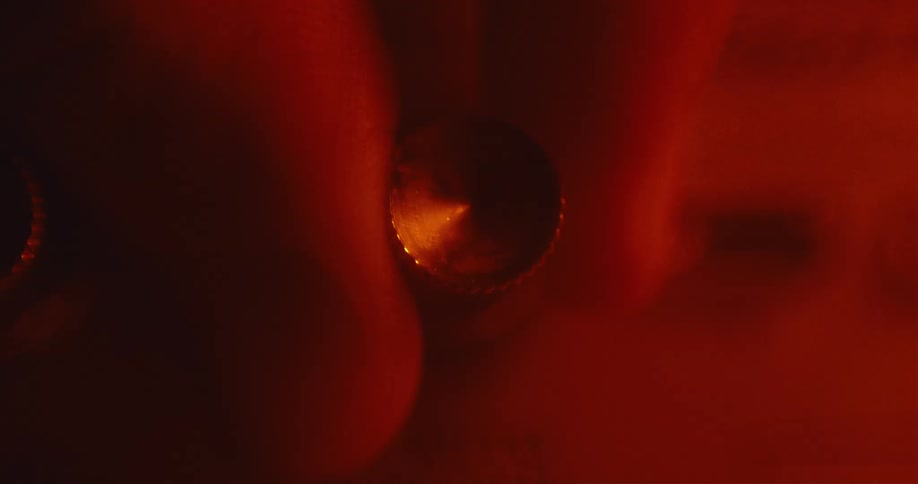 Red light shines as a persons fingers turn a dial on a device