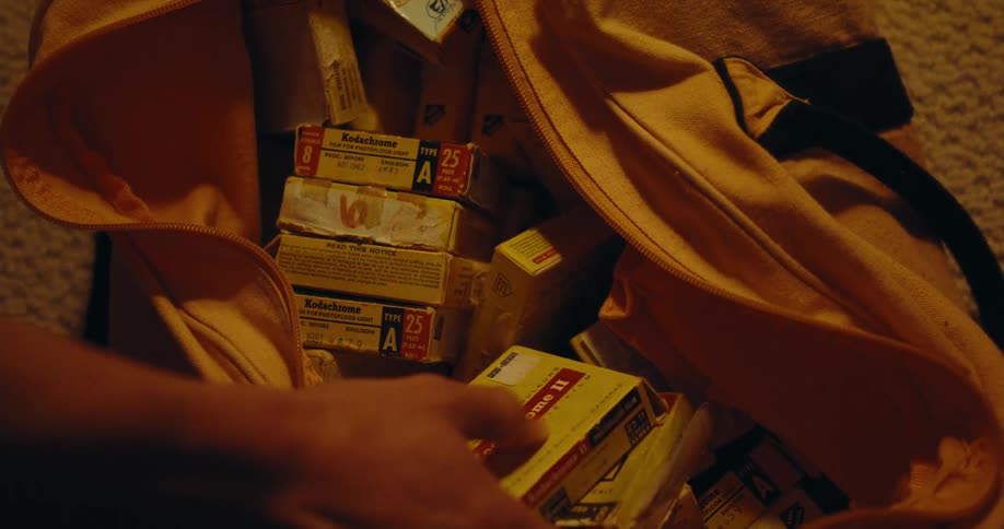 Man opens a yellow duffel bag filled with vintage kodak photographic film
