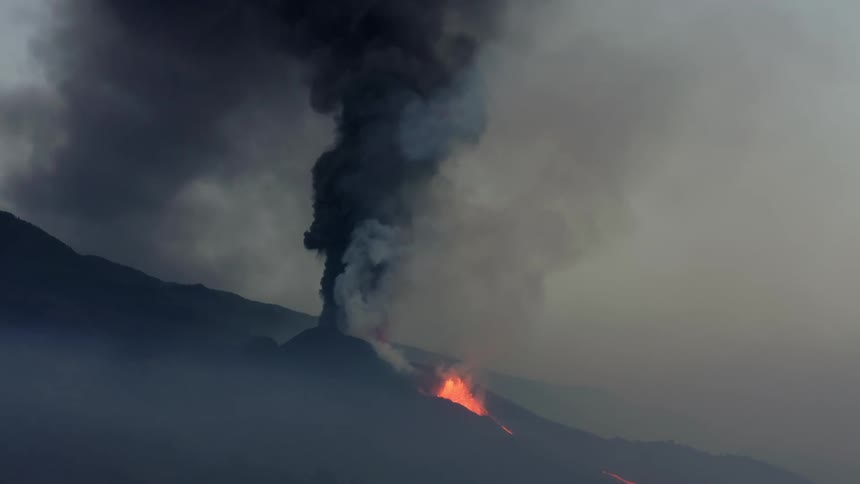 Black smoke rises from a fire on the side of a mountain