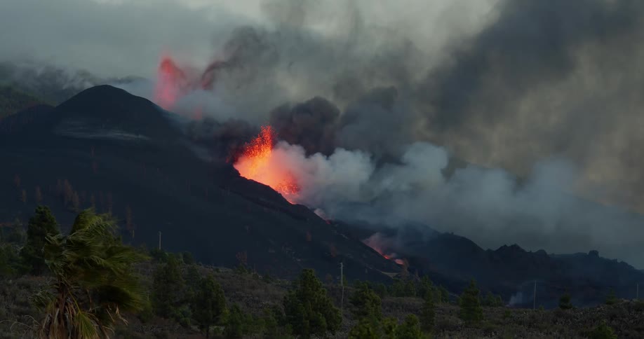Black smoke rises from the fires on the side of a mountain