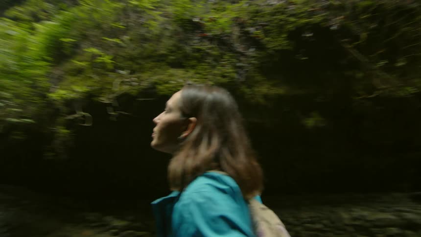 Drone shot of a woman taking pictures with a camera of a waterfall on a ravine