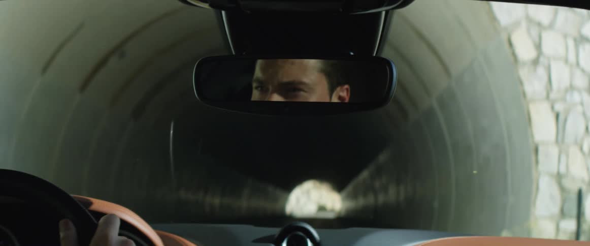 Reflection on the rearview mirror of a man driving a luxury car into a tunnel