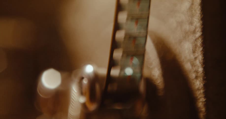 A vintage filmstrip with a photo of a person on it moves through a machine