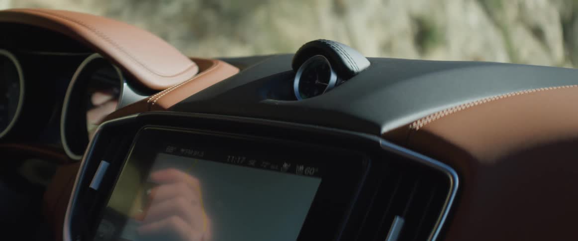 Close up of the screen and clock on the dashboard of a luxury vehicle driving near a cliff