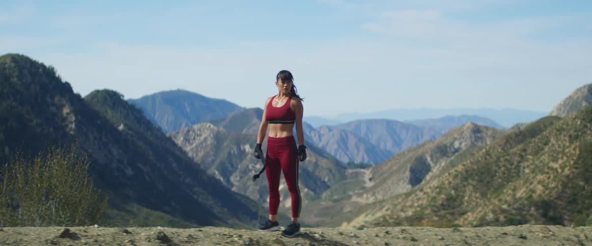 A woman in athletic gear is standing on a mountain top