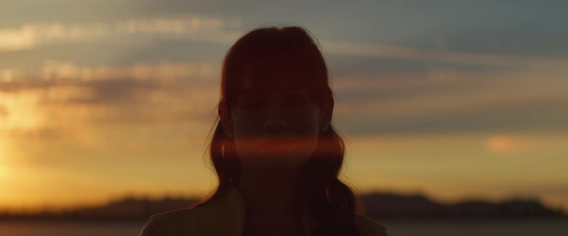 Woman with wavy hair looks into space at sunset