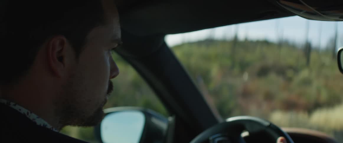 A man drives a car through the countryside during the day