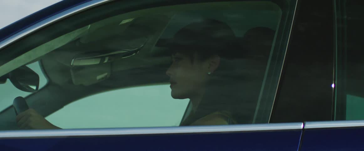 The driver side window of a car with a woman driving