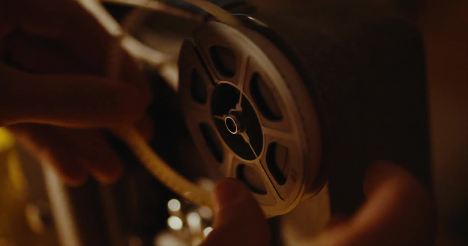 A person puts a film reel on a projector