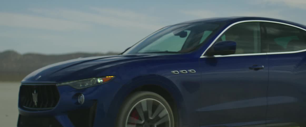 Man drives gray car next to blue car with woman in the field