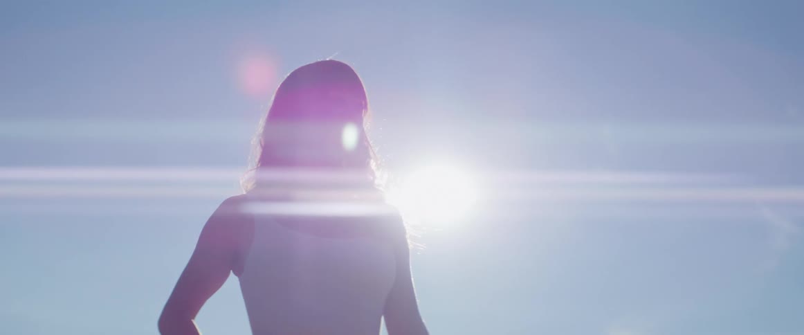 A woman poses outdoors under a clear sky on a sunny day