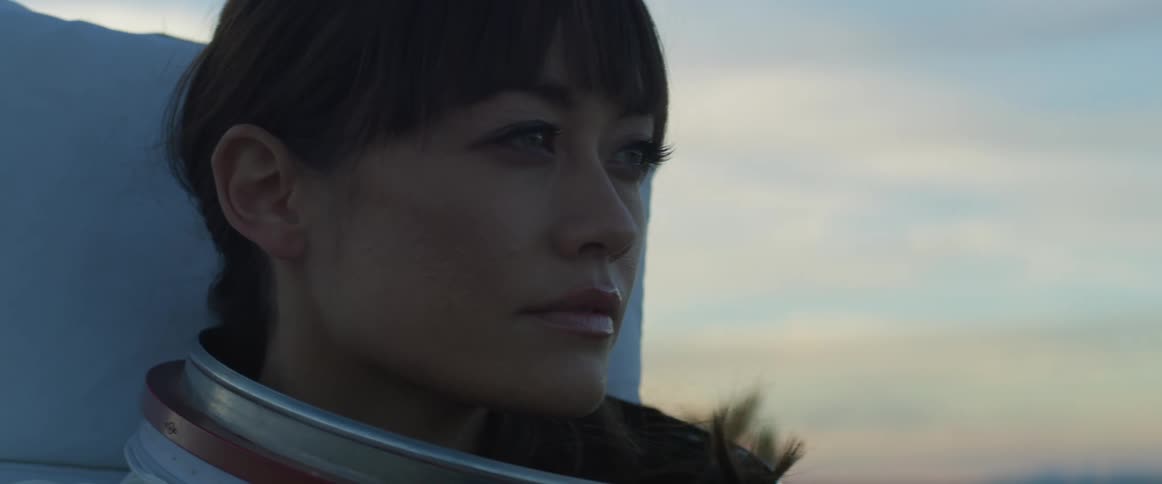 A woman is standing outdoors while the sun is setting