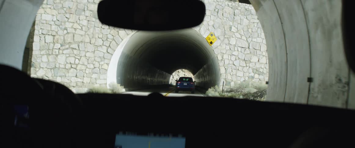 One car with a gps screen follows another car through a tunnel