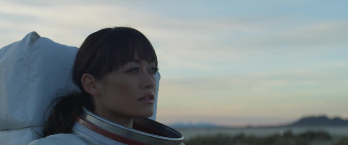 A female astronaut stands and looks around the landscape