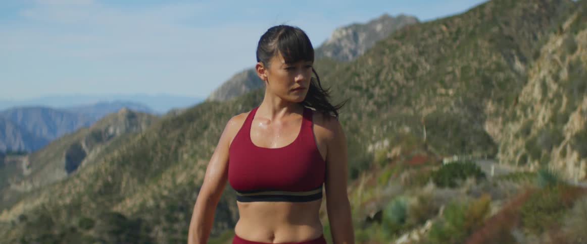 A woman is taking a break from exercising and is breathing hard and sweating up on a mountain