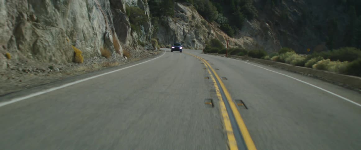 A car drives on a mountain road then into a tunnel