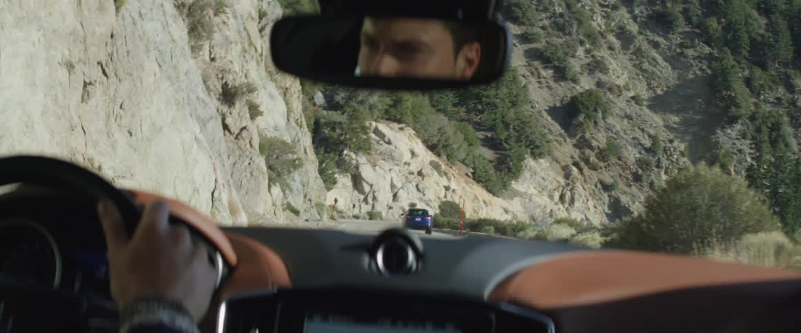 Vehicle inside a tunnel drives through the exit on a mountain road