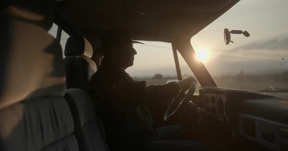 A man sits in his pickup truck while parked in the desert
