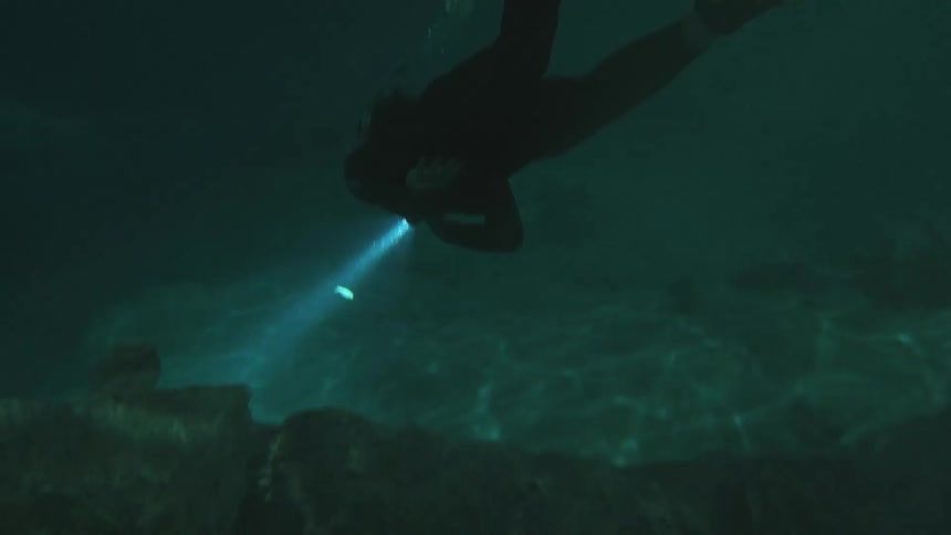 A free diver descends into an underwater cave